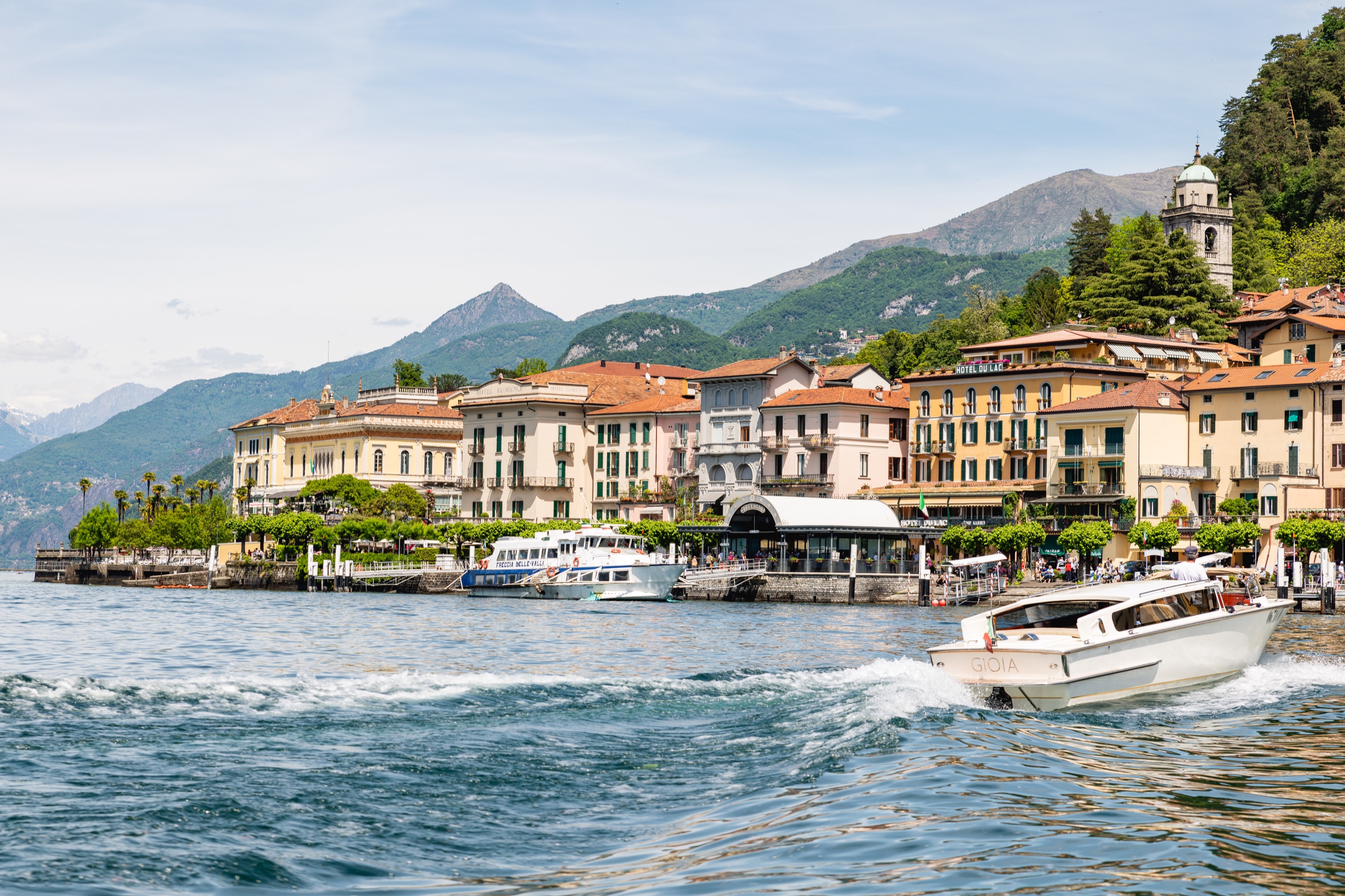 A private boat crossing Lake Como in front of Bellagio and the surrounding mountains