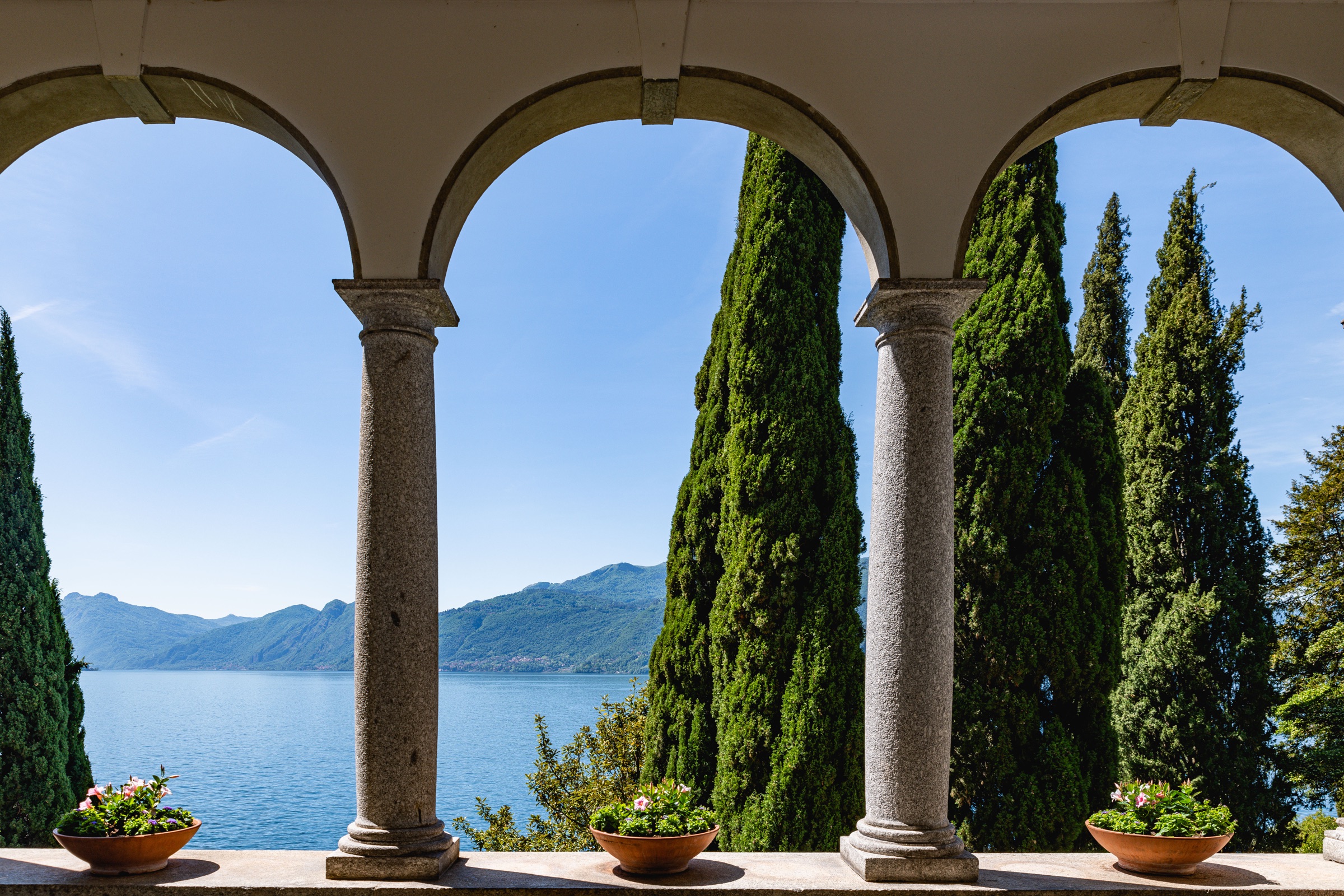 Stone arches framing Lake Como and cypress trees